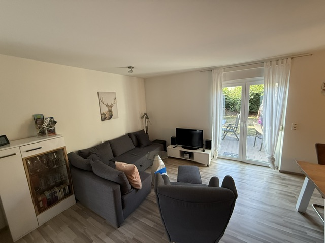Wohnzimmer mit TV und grauer Schlafcouch im M&M Ferienapartment Ludwigshöhe